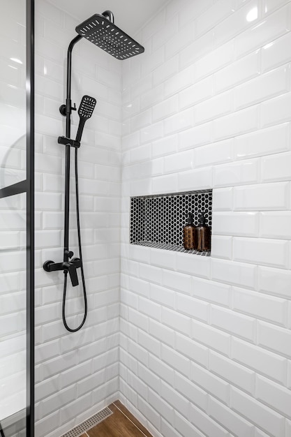 Photo new black shower head on holder in white tiled bathroom in modern apartment