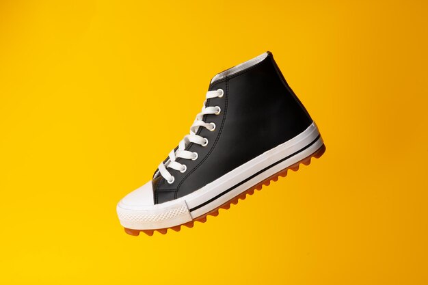 New black and white canvas sneakers on yellow background