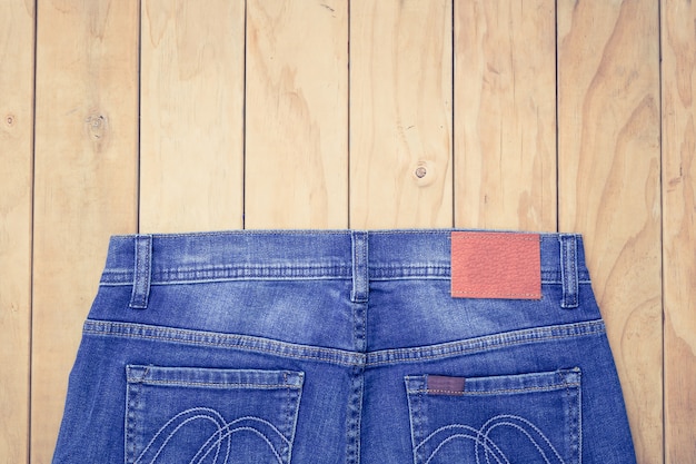 Photo new blue jeans on wooden background top view