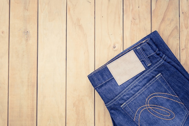 New blue jeans on wooden background top view