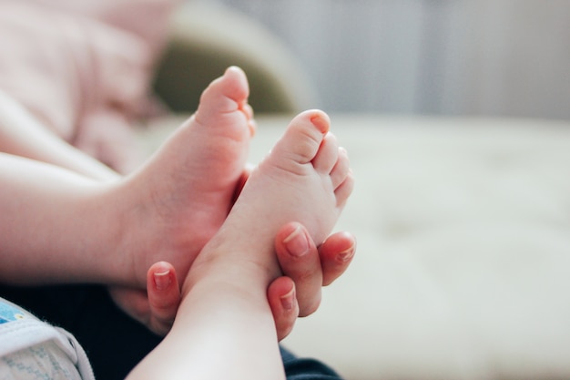 女性の母親の手で生まれたばかりの赤ちゃんの足をクローズアップ