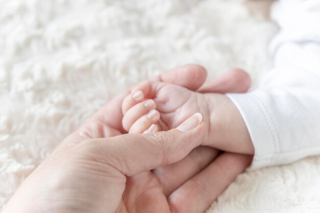 New born baby hand holding mom finger on bed