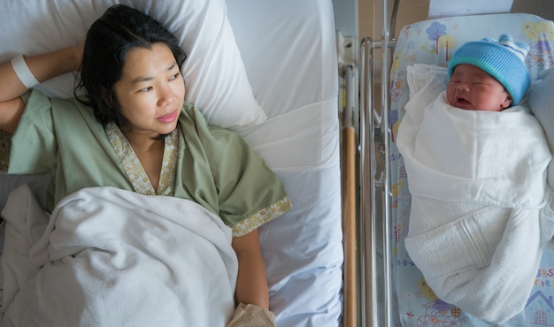 Photo new born baby sleeps with his mother in hospital