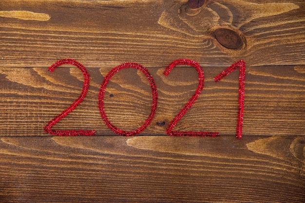 New brown wooden surface made of dark natural wood with red\
christmas numbers 2021