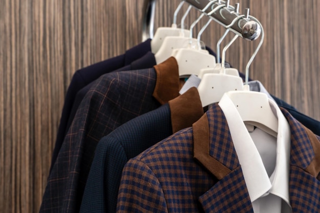 New business men's suits are hanging on hangers in the store Modern fashionable clothes A luxury store with mens clothing Designer business suits