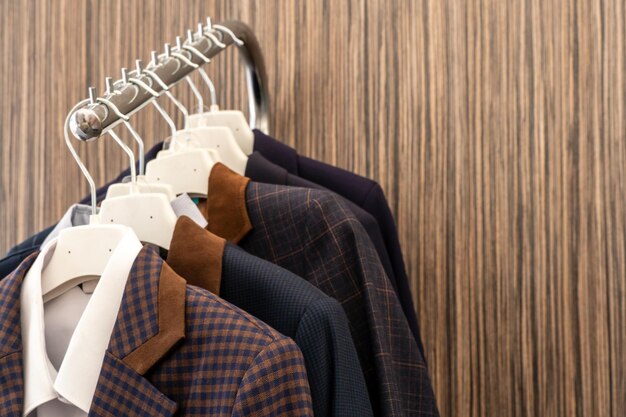 New business men's suits are hanging on hangers in the store Modern fashionable clothes A luxury store with mens clothing Designer business suits