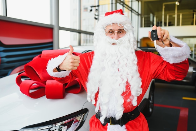 New car as a Christmas present. Santa Claus in the car showroom near a new car.