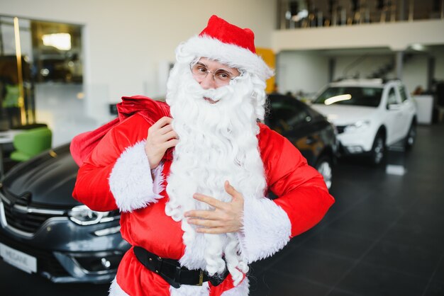 New car as a christmas present. santa claus in the car showroom near a new car