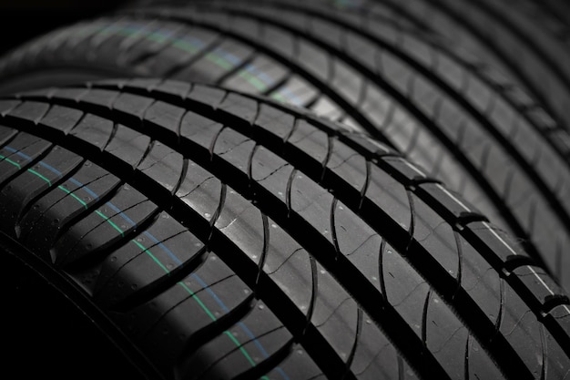 Photo new car tires group of road wheels on dark background summer tires with asymmetric tread design driving car concept closeup