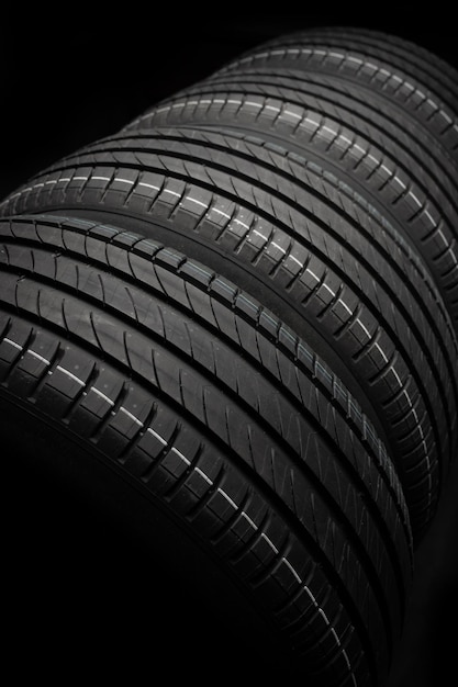 새 자동차 타이어 어두운 배경의 도로 바퀴 그룹 비대칭 트레드 디자인이 있는 여름 타이어 운전 자동차 개념
