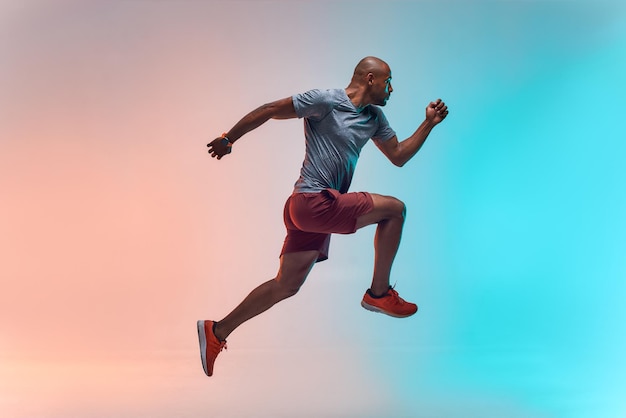 New champion full length of young african man in sports clothing jumping against colorful background