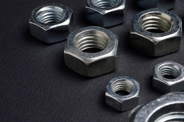 new chrome nuts of different sizes are laid out against a dark background. close-up.