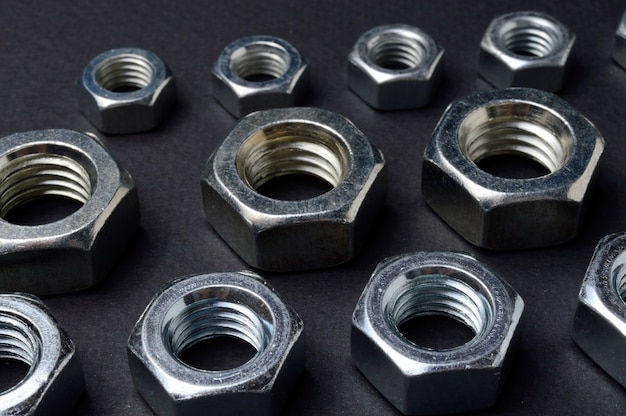 new chrome nuts of different sizes are laid out against a dark background. close-up.