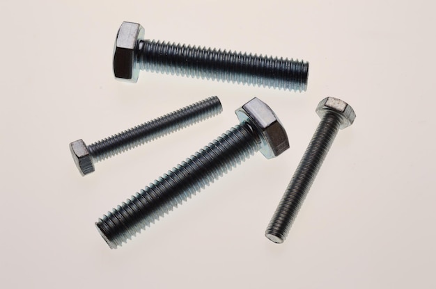 New chromeplated bolts and nuts of different sizes lie on a white background Closeup