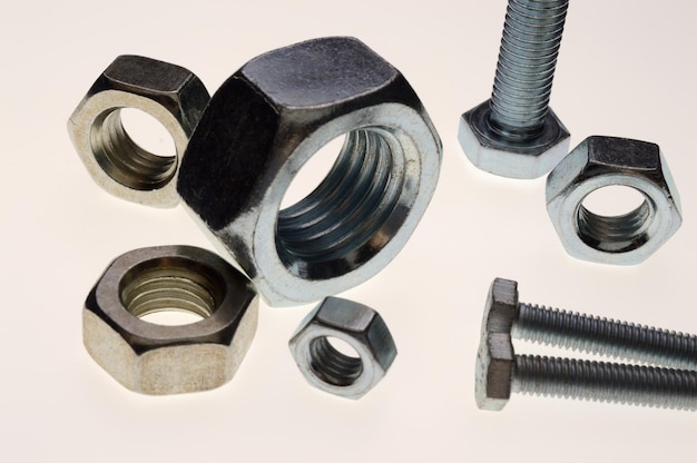 New chromeplated bolts and nuts of different sizes lie on a white background Closeup