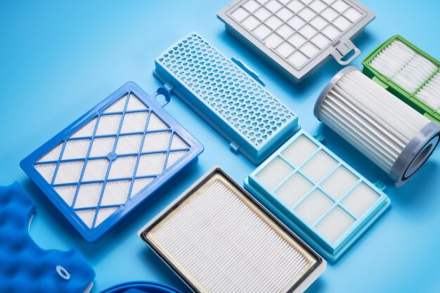 Новые чистые пылевые воздушные фильтры для пылесоса, изолированные на синем фоне