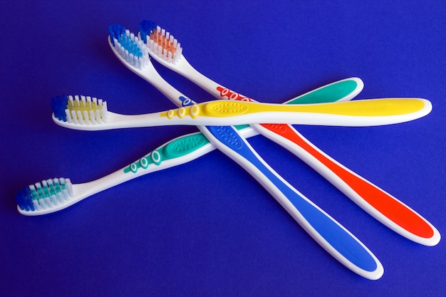 Photo new colorful toothbrushes on a blue background. concept - oral hygiene.