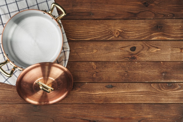 New copper cooking pot on wooden table, view from above