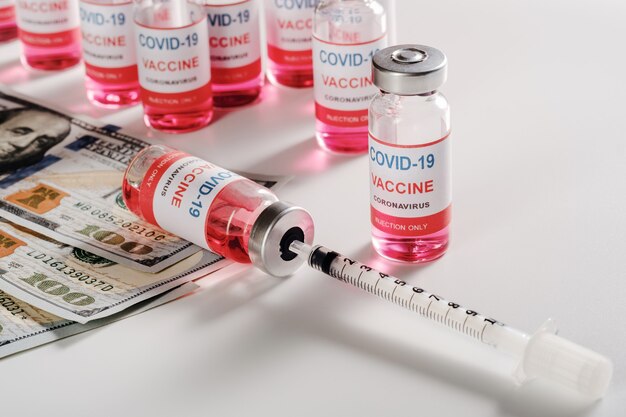 달러 지폐와 충전 주사기가있는 새로운 코로나 바이러스 백신