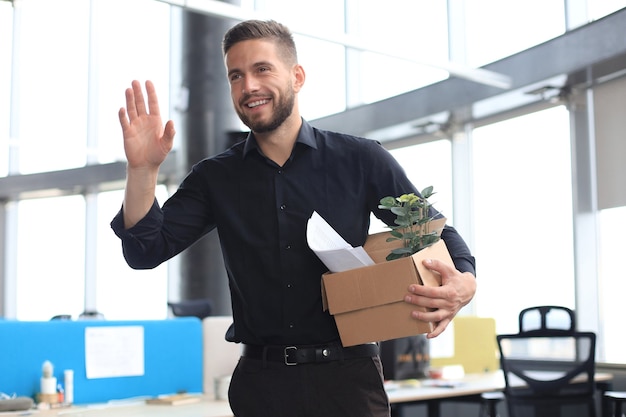 New employee in modern large office is carrying box full of papers and documents for job.