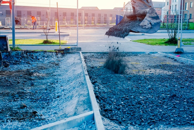 A new footpath is under construction as builders bring stone levelling it and compacting