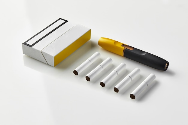 Черно-желтая электронная сигарета нового поколения, одна упаковка и пять палочек, изолированных на белом Новая альтернативная технология Система нагревания табака Макет рабочей области рекламной зоны Закрыть