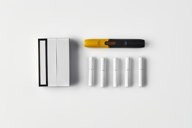 Черно-желтая электронная сигарета нового поколения, одна упаковка и пять палочек, изолированных на белом. Новая технология. Система нагревания табака. Шаблон места для текстового изображения.