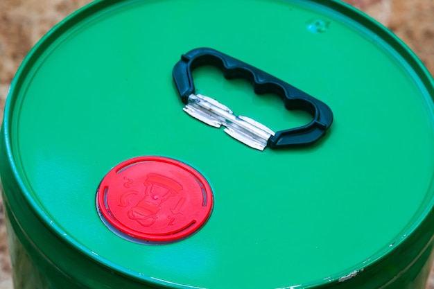 A new green sealed bucket of fuel oil with a red cap and a black handle on top