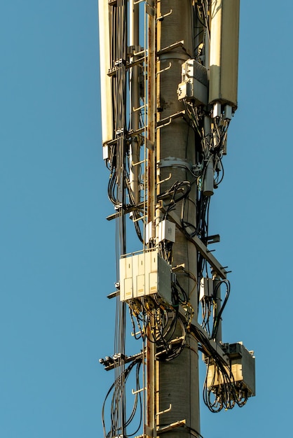 New gsm antennas on a high tower against a blue sky for\
transmitting a 5g signal are dangerous to health radiation\
pollution of the environment through cell towers the threat of\
extinction