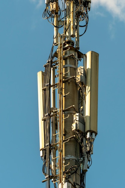 New gsm antennas on a high tower against a blue sky for\
transmitting a 5g signal are dangerous to health radiation\
pollution of the environment through cell towers the threat of\
extinction