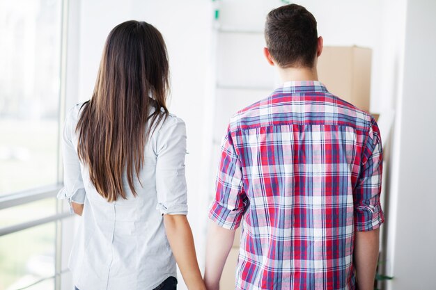 New Home. Funny young couple enjoy and celebrating moving to new home. Happy couple at empty room of new home