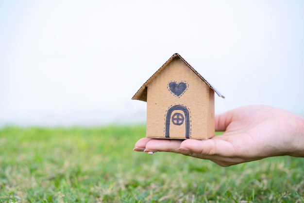 New home and house concept Cardboard house model outdoors in female hand