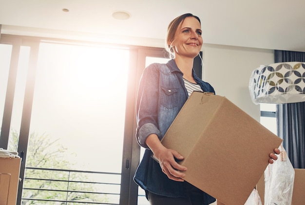New home moving and happy woman holding box for property sale mortgage or investment Real estate package and person with cardboard for relocation unboxing or packing in apartment with lens flare