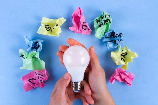 Photo new idea concept, crumpled paper balls and light bulbon in hands