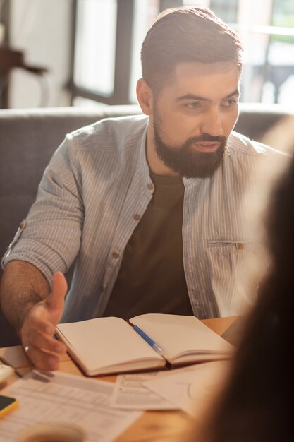 Photo new ideas. handsome smart man sharing his innovative ideas while sitting with a notebook in front of him