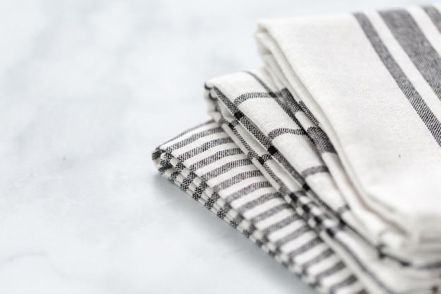 New kitchen towels with simple black pattern folded on marble counter.