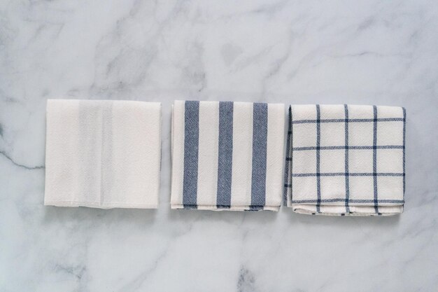 New kitchen towels with simple blue pattern folded on marble counter.