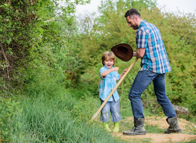 New life. soils and fertilizers. father and son planting family tree. rich natural soil. Eco farm. Ranch. happy earth day. Dig grounf with shovel. small boy child help father in farm. family business.