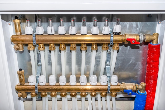 Photo new manifold of underfloor heating system plastic pipes and valves visible serving nine circuits