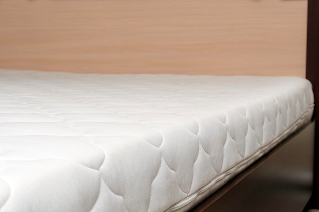 New mattress on a wooden bed side view The concept of buying or producing mattresses