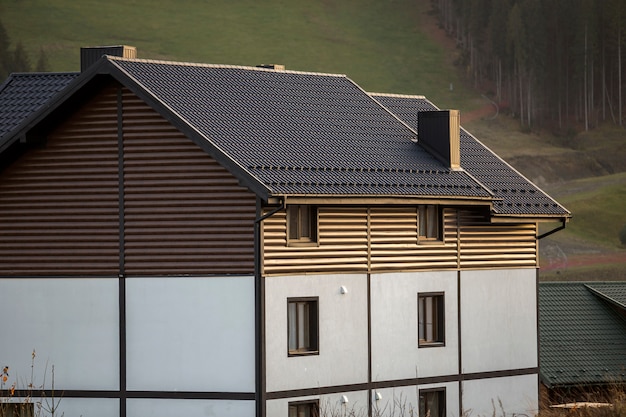 New nice white and brown two-storied cottage with shingle roof in ecological area on foggy wood and hills  on sunny summer day. Well maintained property, real estate concept.