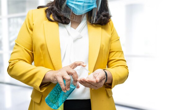 New Normal Asian working woman washing hand by press blue alcohol sanitizer gel for protect safety infection and kill Covid19 Coronavirus in office