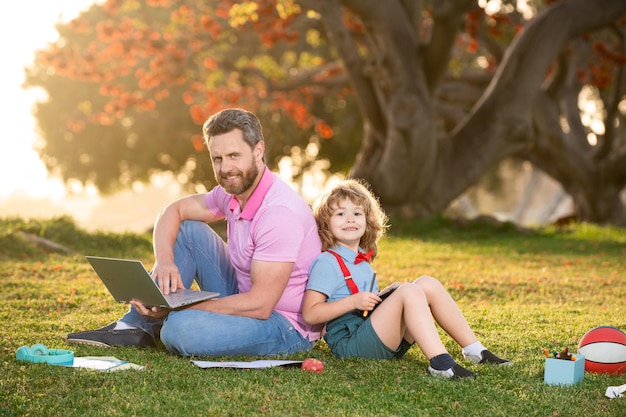 New normal back to school elementary scholar pupil sitting with teacher on grass