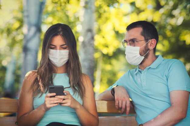 New normal concept after the pandemic a couple view with their mask Woman typing a message and man is watching her