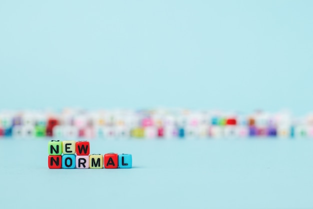 NEW NORMAL word with letter beads on blue background