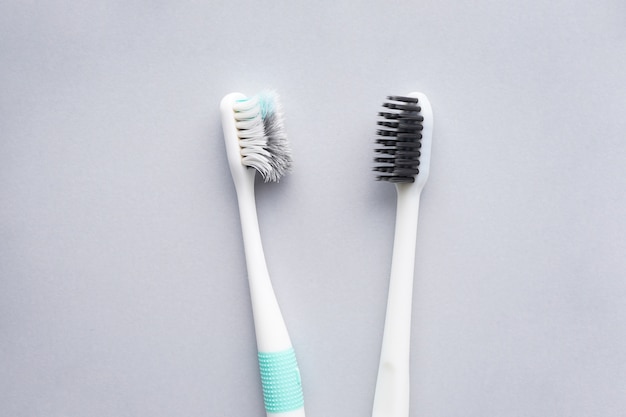 New and old toothbrushes on gray