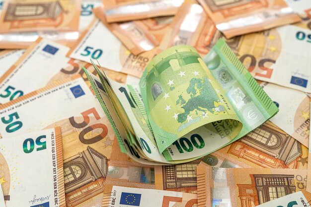 New orange banknotes of 50 euros are scattered on the table and on them lie acurant banknotes of 100 euros The concept of luxury Currency concept