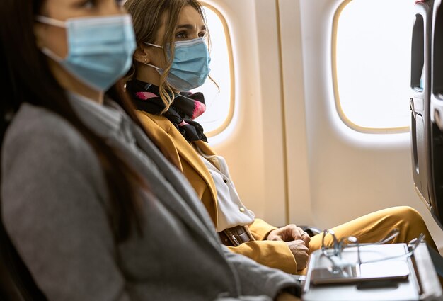 New order in airplane. Woman is sitting in mask before fly