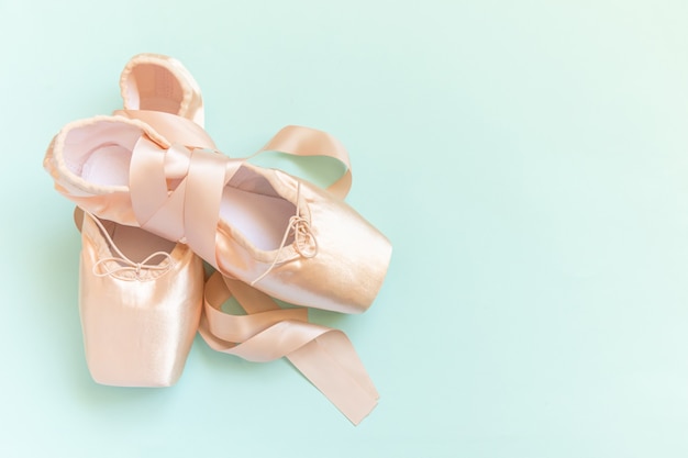 New pastel beige ballet shoes with satin ribbon isolated on blue background