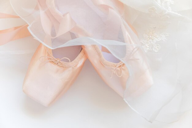 Photo new pastel beige ballet shoes with satin ribbon and tutut skirt isolated on white background